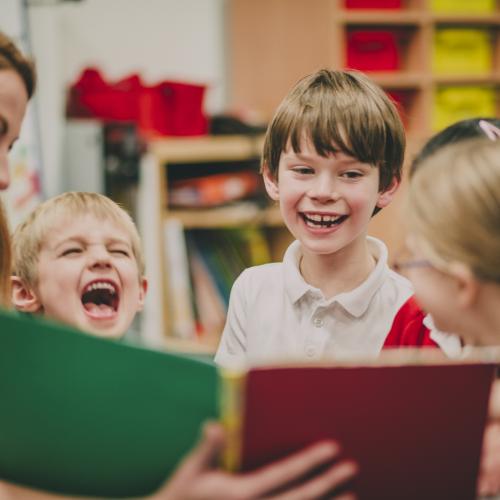 Une femme montre des livres à un groupe d'enfants qui rient