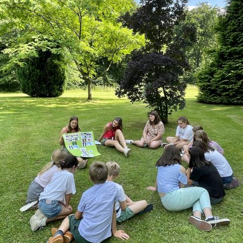 Un groupe de jeunes ados en cours de langue assis dans l'herbe du parc de La Louve