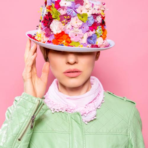 Une femme portant un chapeau piqué de fleurs multicolores