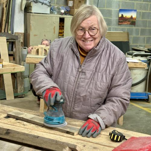 Une participante souriante, en train de poncer un morceau de palette en bois