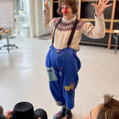 Une femme grimée en clown, les mains levées