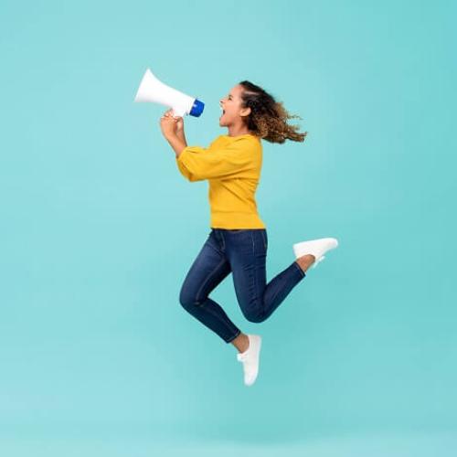 Une femme saute en même temps qu'elle hurle dans un mégaphone