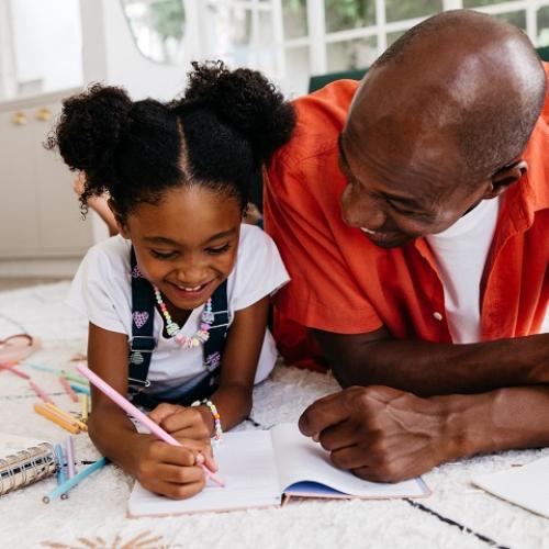 Un homme et une petite fille écrivent ou dessinent sur un cahier