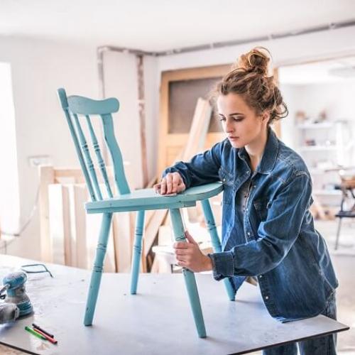 Une femme en train de patiner ou peindre une chaise en bois