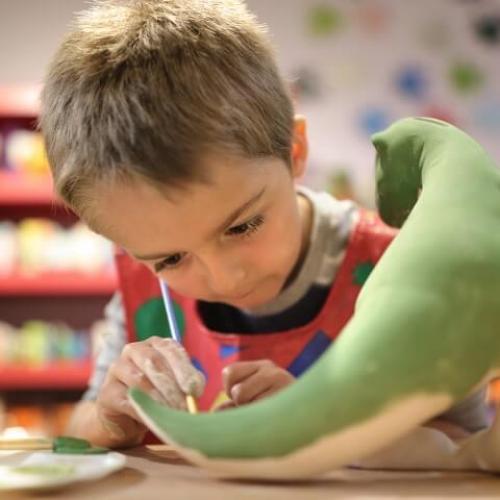 Un petit garçon concentré sur la peinture d'un dinosaure en 3D
