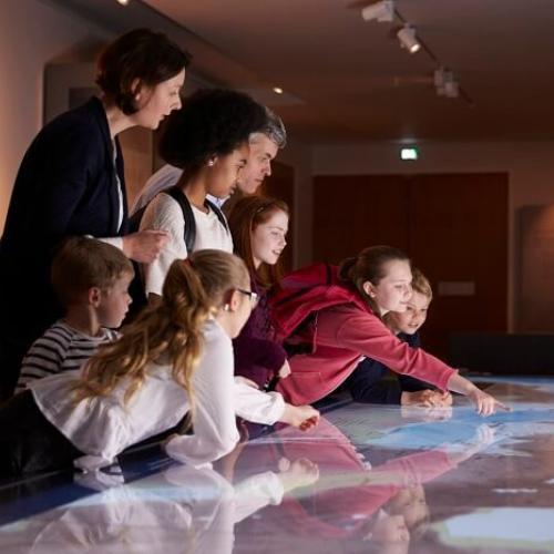 Un groupe d'enfants autour d'une table didactique dans un musée