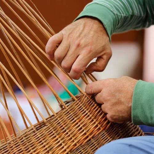 Des mains en train de tresser du saule pour réaliser un panier